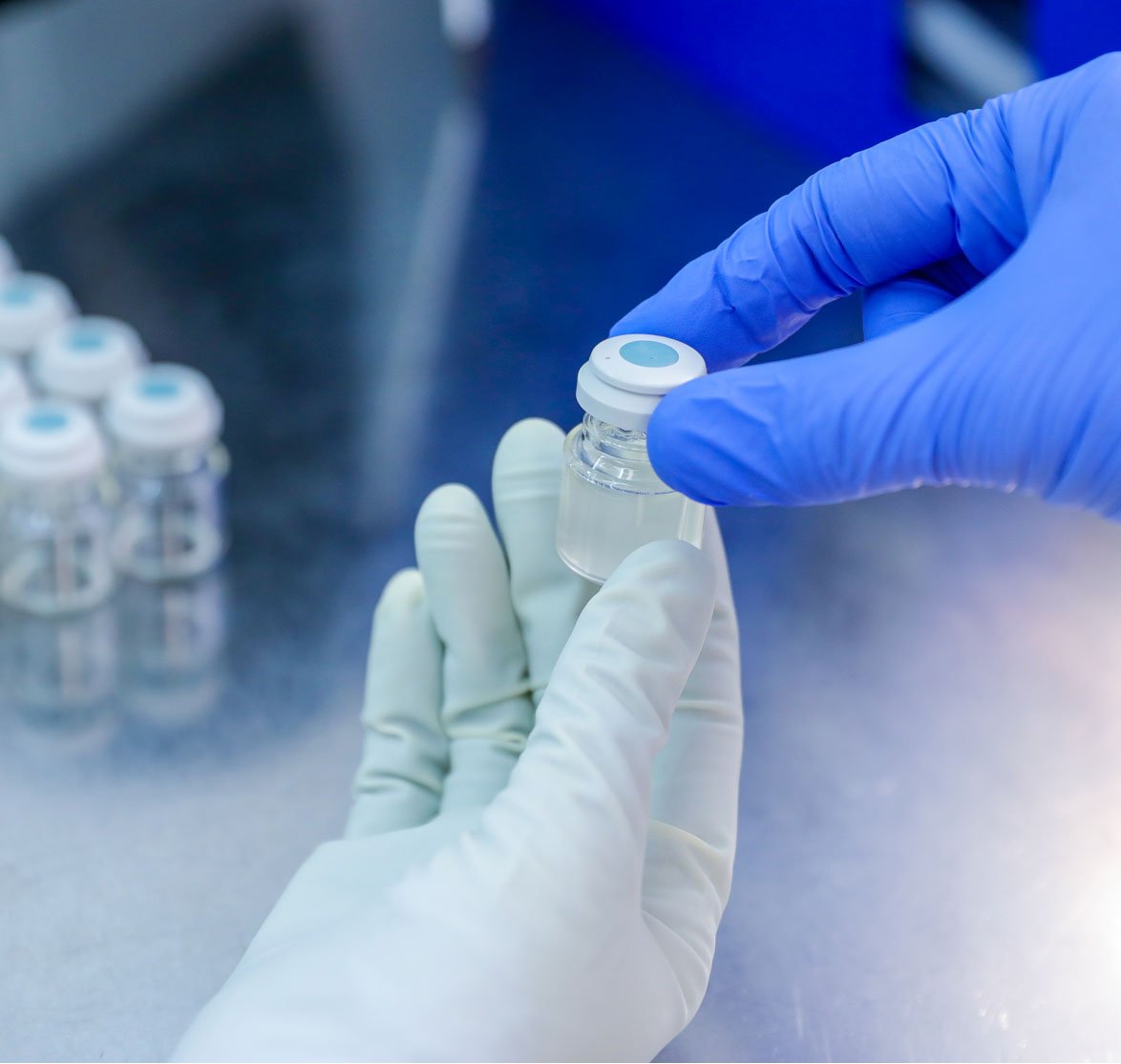 Hand with medical glove holding a bottle vaccine